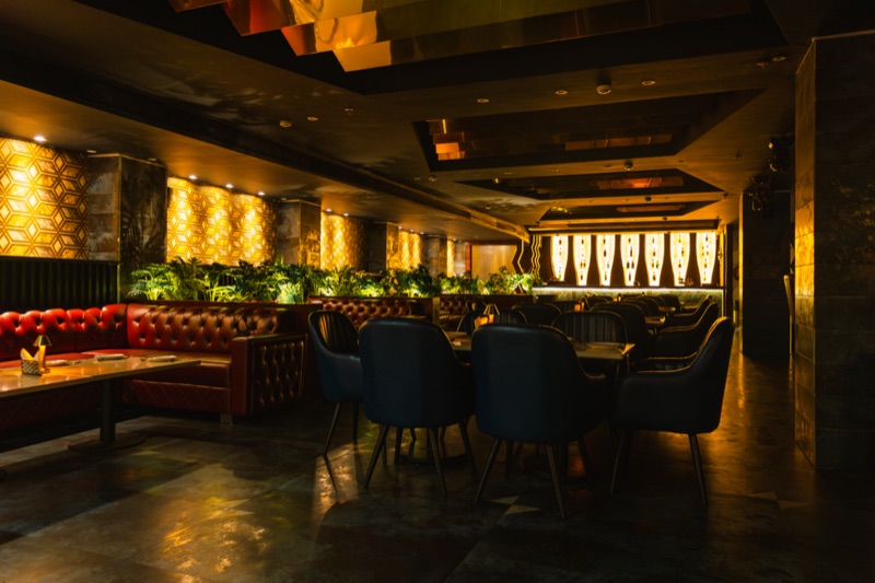 The Bellers dining room: red booths, blue velvet chairs and the lit bottle wall