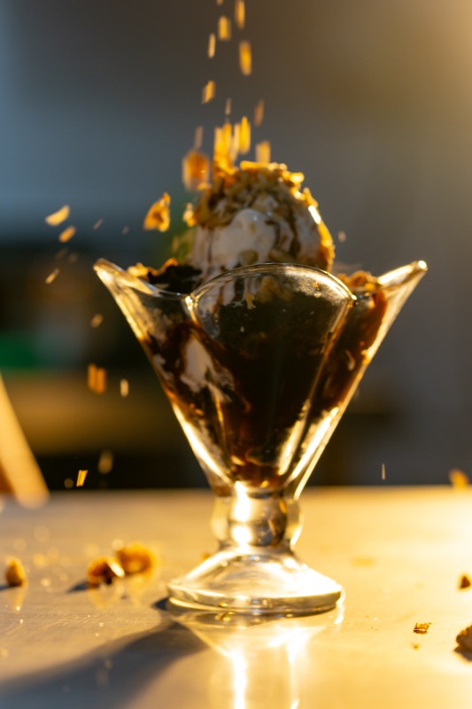 Chopped nuts frozen mid-fall onto a chocolate sundae in a tulip glass at The Grand Ambassador