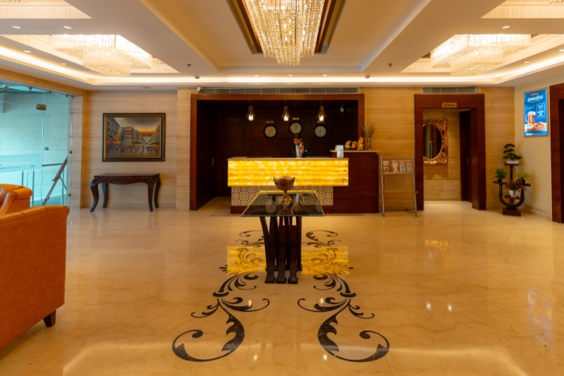 The hotel lobby: a marble floor with a dark inlaid pattern leading to a glowing onyx reception desk