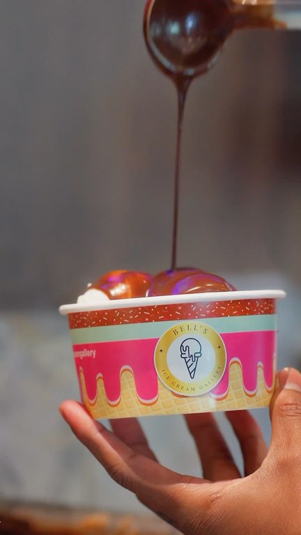 Reel: chocolate over a sundae, a scoop into a cup, mango on the cold stone and a pistachio drizzle