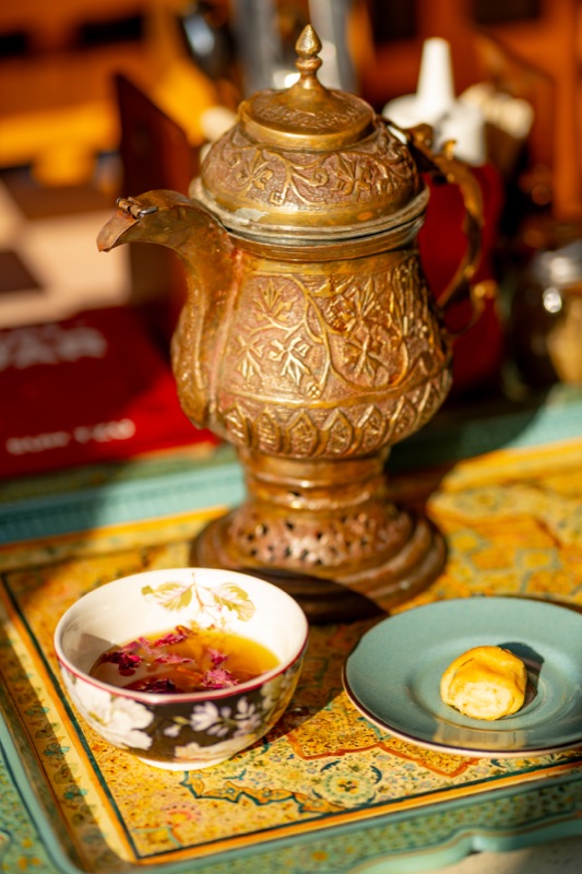 A brass samovar and a cup of kahwa with rose petals at Koh Zeen