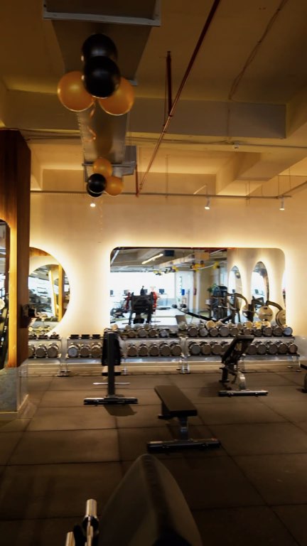 Film: a slow glide across the strength floor past a red bumper plate and a row of lit round mirrors