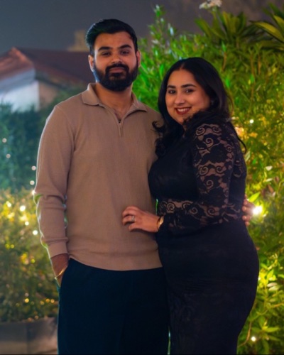 Aditya Vashistha and Navneet Kaur, at night in a garden strung with small lights: Aditya bearded, in a beige knit polo