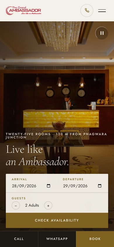 The Grand Ambassador’s website on a phone: the hotel’s reception, “Live like an Ambassador.” and a box to check availability