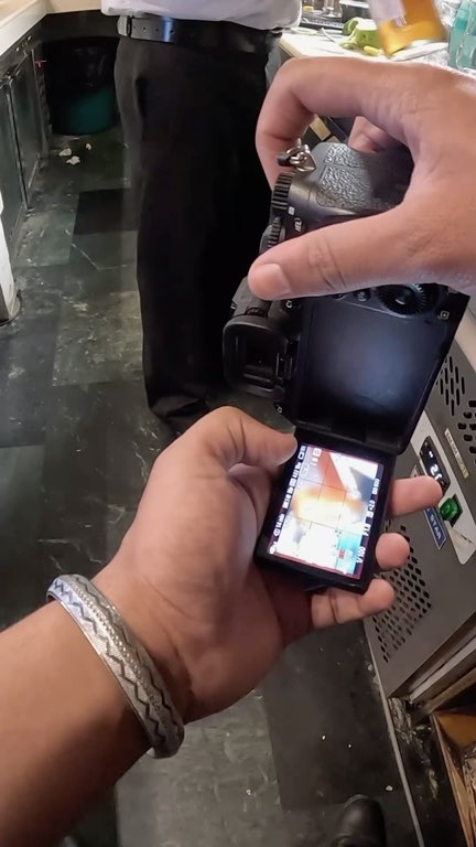 Hands setting up a camera with a flip-out screen at a hotel bar, then a slow pour over ice